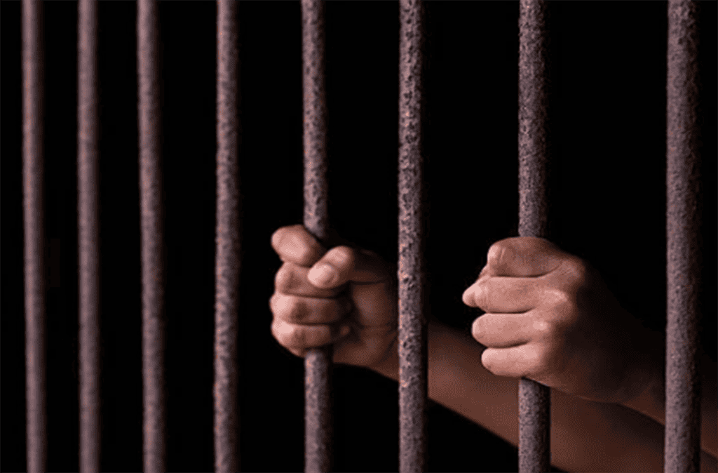 Hands gripping prison bars, symbolizing incarceration issues.
